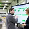 Mitarbeitende in Smart Factory vor einem Daten-Display
