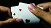 Closeup of a person hand holding a pair of aces against a dark b