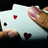Closeup of a person hand holding a pair of aces against a dark b