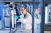 Frau in Laborkittel und Schutzbrille an einem Laborgerät; Das neue automatisierte Labor von Covestro kann 24 Stunden am Tag, 7 Tage die Woche arbeiten. Ziel sind zehntausende Tests pro Jahr.