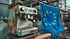 Verrostete Maschine und daneben eine Europa-Flagge