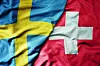 big waving national colorful flag of sweden and national flag of switzerland .
