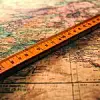 A ruler lying across a map, indicating measurement for a travel route or geographical survey