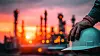 Worker Hand Holding Safety Helmet At Sunset Oil Refinery