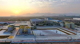Weitwinkelansicht eines Industrieareals bei Sonnenaufgang mit mehreren Gebäuden und Anlagen.