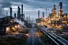 Fotorealistisches Weitwinkelbild eines industriellen Chemieclusters: links ältere, teilweise stillgelegte Anlagen mit gedimmten Lichtern und abgesperrten Bereichen, rechts eine moderne, neu wirkende Anlagensektion mit aktiver Beleuchtung und sichtbaren Baustellen-Elementen