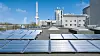 Reihen von Solarpaneelen als Fotoreaktoren auf einem Flachdach vor Industriegebäuden