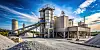 Industriewerk für Beton und Zement mit Silos, Förderband und Schotter im Vordergrund.