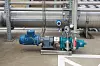 Elektrische Industriepumpe mit Armaturen und Messgeräten vor großen Metallrohren