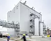 Moderne Industrieanlage mit Silos, Rohrbrücken und Mitarbeitenden in Schutzkleidung