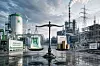 Waage mit Wasserstoffbehälter und Münzstapeln vor moderner Industrie- und Energieanlage.