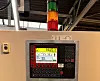 Industrie-Steuerpult mit Display und Signalleuchte in einer Fabrikhalle