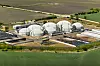 Luftbild einer Biogasanlage mit weißen Kuppeltanks inmitten von Feldern