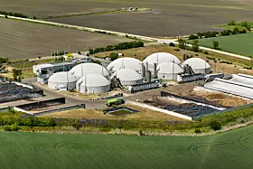 Luftbild einer Biogasanlage mit weißen Kuppeltanks inmitten von Feldern