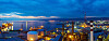 Blick auf einen Industriehafen mit Kränen, Schiffen und Lichtern bei Dämmerung.