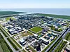 Luftaufnahme eines großen Küstenkomplexes mit Straßen, Gebäuden und Grünflächen am Meer.