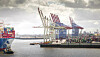 Containerhafen mit Frachtschiff, Hafenkränen und gestapelten Containern in der Region Rotterdam.