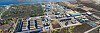 Luftbild einer großen Industrieanlage mit Hallen, Verkehrswegen und Küste.