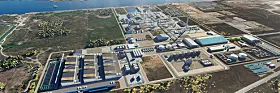 Luftbild einer großen Industrieanlage mit Hallen, Verkehrswegen und Küste.