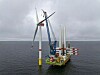 Installationsschiff montiert eine Offshore-Windkraftanlage im Meer bei bewölktem Himmel.