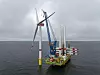 Installationsschiff montiert eine Offshore-Windkraftanlage im Meer bei bewölktem Himmel.