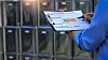Focused inspector conducts safety inspection of chemical storage cabinet holding clipboard document inside industrial facility