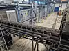 Förderanlage mit Metallgestellen und Rohrleitungen in einer Produktionshalle.