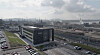 Weitwinkelansicht eines Industriegebiets mit Bürogebäude, Straßen und Hafen im Hintergrund.