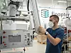 Mitarbeiter mit Maske überprüft eine Maschinenanlage in einer Werkhalle.
