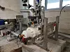 Industrielle Rohrleitungen und eine montierte Maschineneinheit in einem Werkraum.