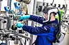 Techniker mit Helm und Handschuhen arbeitet an Rohrleitungen und Ventilen in einer Industrieanlage.