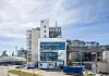 Große Industrieanlage mit Gebäuden, Rohrleitungen und Metallkonstruktionen bei klarem Himmel.