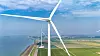Windräder an einer Küste neben Wasser, Deich und grünen Feldern; Der Onshore-Windpark Karolinapolder am Volkerak bei Dinteloord stellt Strom aus erneuerbarer Quelle für die Wasserstoffproduktion von Air Products bereit.