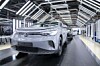Silberner Volkswagen auf einem Förderband in einer modernen Autofabrik.