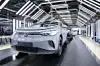 Silberner Volkswagen auf einem Förderband in einer modernen Autofabrik.