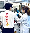 Zwei Personen in Laborkitteln arbeiten an einer technischen Anlage im Labor.