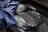 Behandschuhte Hände halten schwarzes Pulver aus Fahrzeugbatterien.