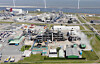 Luftbild eines Industriekomplexes an der Küste mit Gebäuden, Straßen und Dampf.