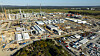 Luftbild einer großen Industriebaustelle mit Kränen, Gebäuden, Rohren und Baucontainern.