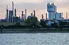 Industrielle BASF-Anlage am Flussufer mit hohem Prillturm und mehreren Schornsteinen im Hintergrund.