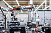 Industrieroboter in einer modernen Fabrikhalle mit Förderband und Monitoren.